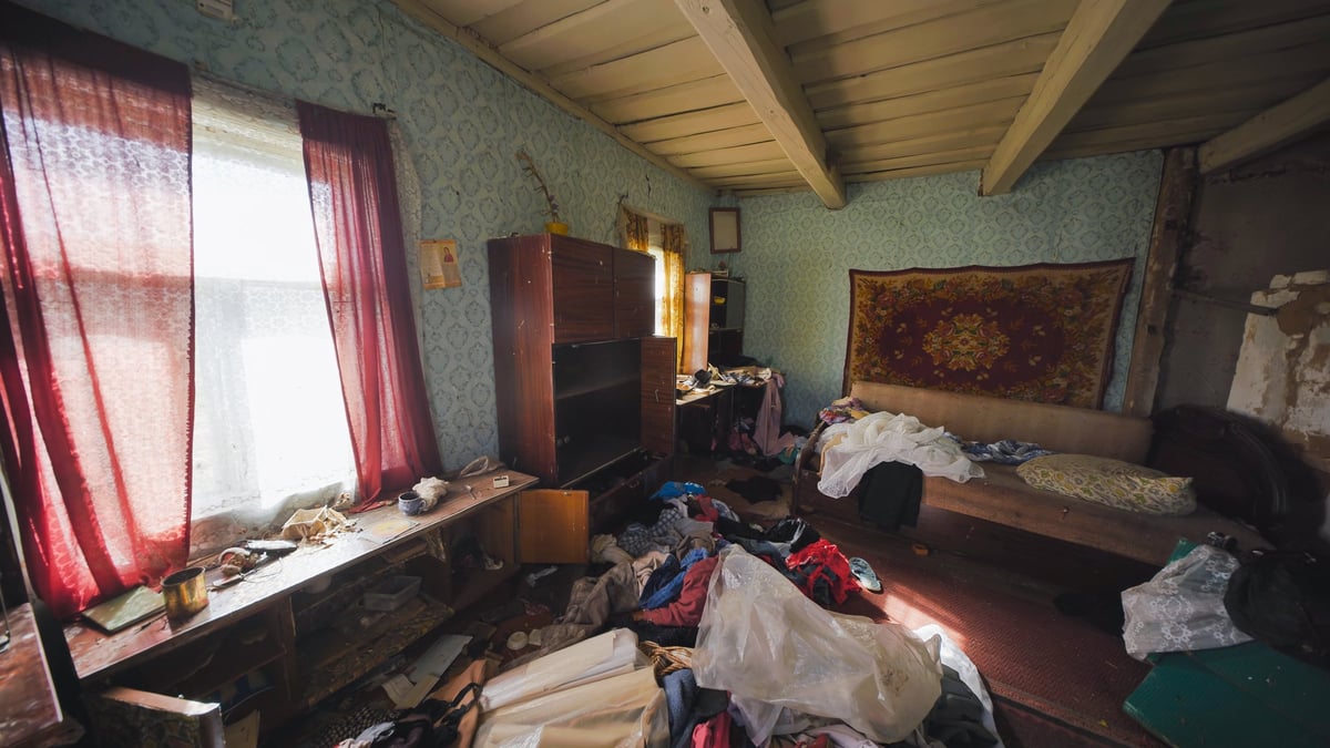 Disorganized room with scattered belongings, reflecting neglect and a sense of decay inside an old house